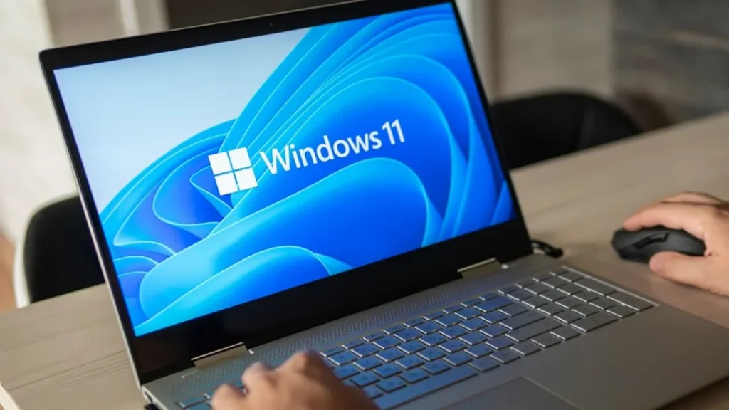 Laptop mit Windows 11 Startbildschirm und Hand an Computermaus während der Einrichtung