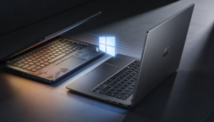 Zwei Laptops stehen nebeneinander auf einer dunklen Fläche. Ein Laptop ist teilweise geschlossen, während der andere geöffnet ist und ein leuchtendes Windows-Logo zeigt, das zwischen ihnen schwebt.