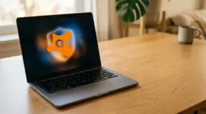 Auf einem Laptop, der auf einem Holztisch steht, ist auf dem Bildschirm das Avast-Antivirus-Logo zu sehen. Im Hintergrund stehen neben einem Fenster eine grüne Pflanze und eine graue Tasse.